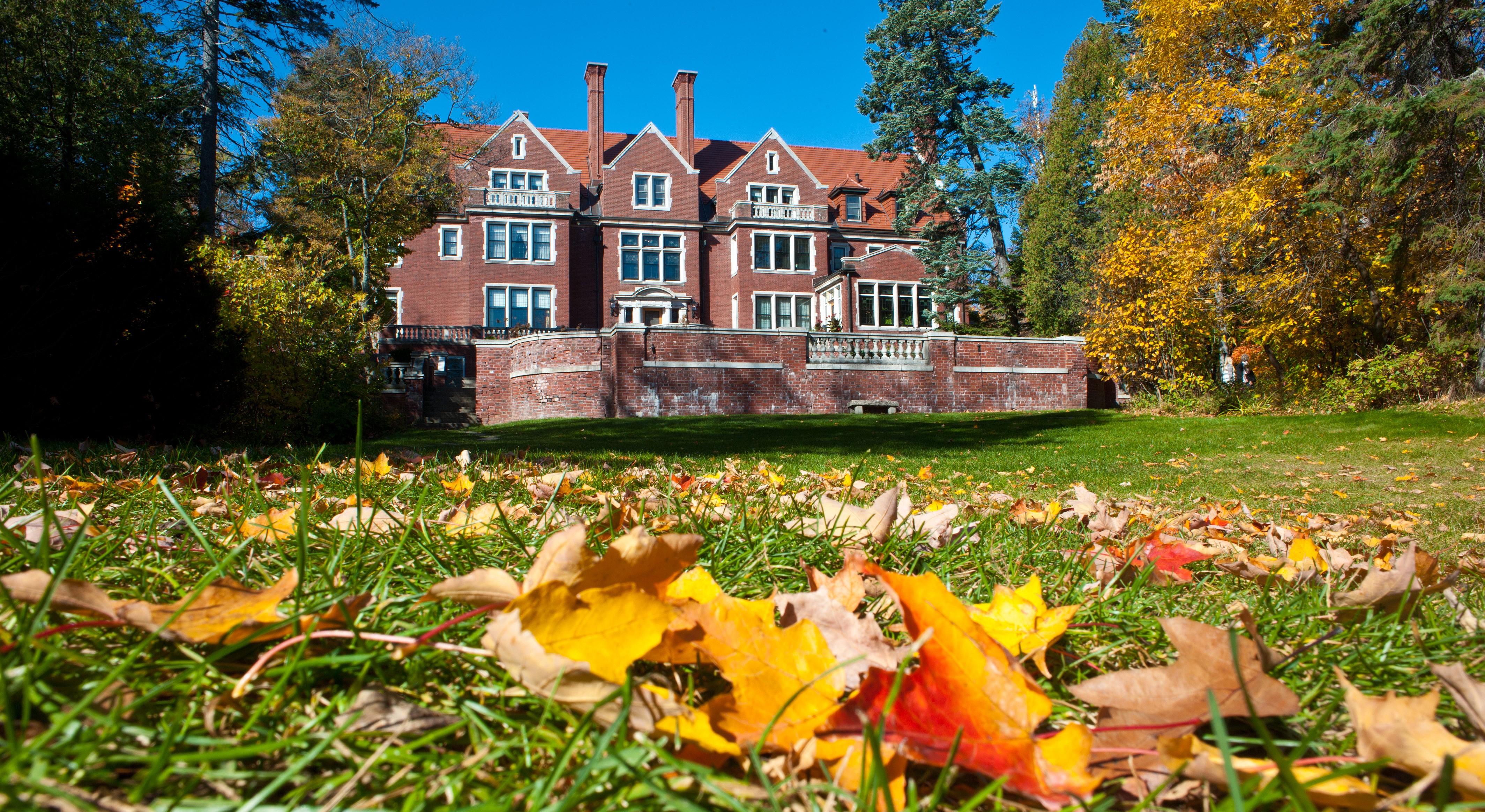 Glensheen Mansion with brightly colored autumn leaves covering the back lawn