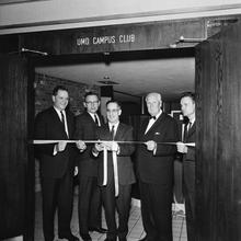 A Black and white photo of five men cutting a ribbon on the UMD Campus Club.